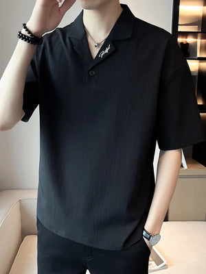 Black cotton polo shirt with embroidered collar detail and button-down neckline.