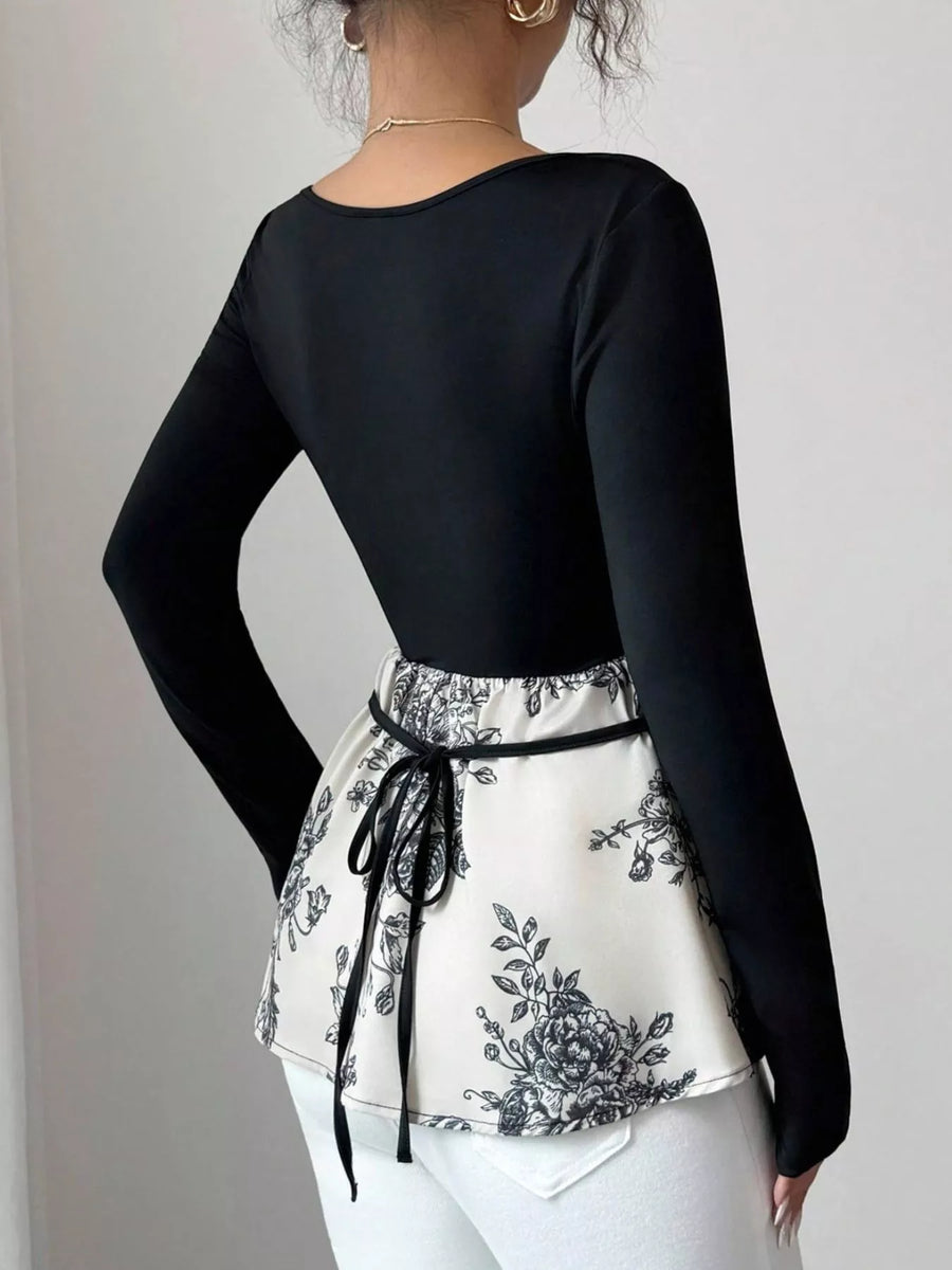 Black long-sleeve top with a peplum hem featuring a black floral print and a tie waist.