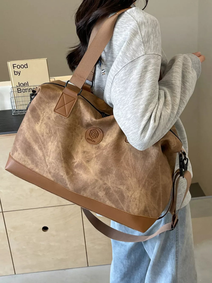 Distressed brown duffle bag with adjustable strap and faux leather trim