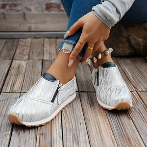 White zebra print slip-on flats with side zippers and dark trim.