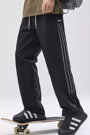 Black wide-leg cargo pants with adjustable drawstring and triple stripe detail on the leg.