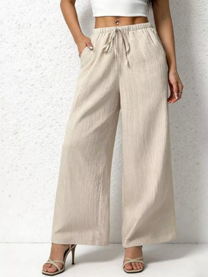 Beige cotton wide-leg pants with adjustable drawstring waist and pockets.