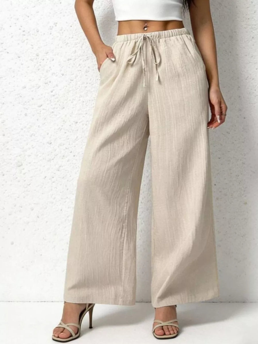 Beige cotton wide-leg pants with adjustable drawstring waist and pockets.