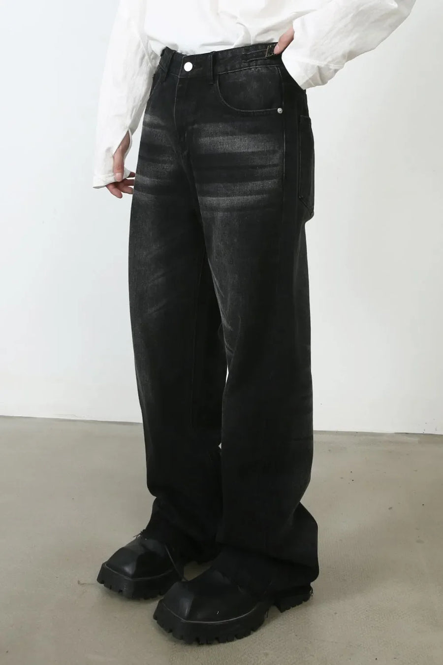 Dark wash barrel leg jeans with whiskering detail, styled with a white shirt and chunky black boots.