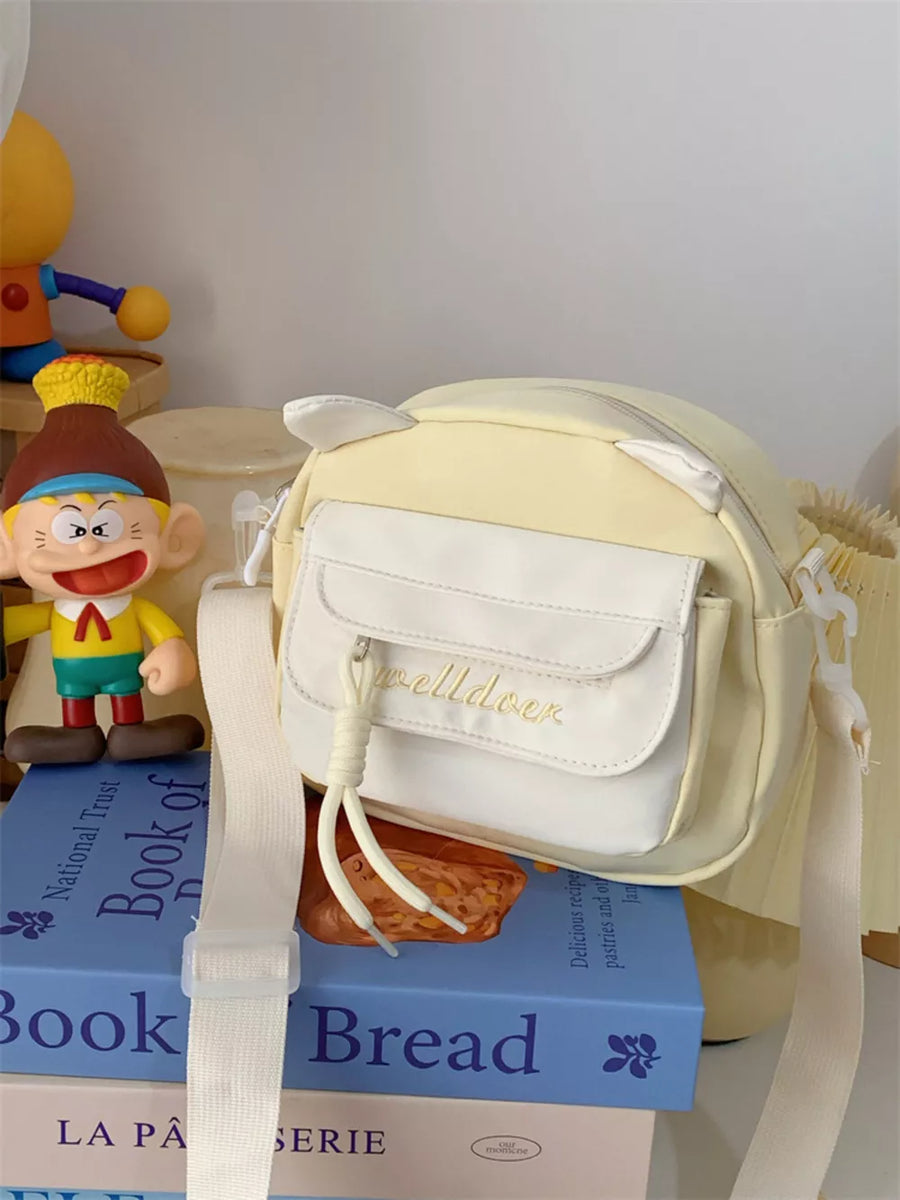 Yellow crossbody bag with cat ears and white pocket detail.