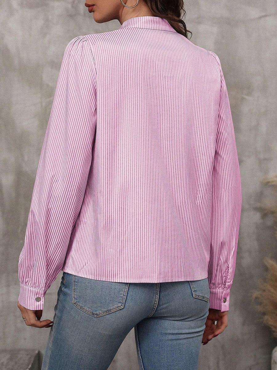 Pink striped blouse with puffed sleeves and button cuffs, styled with jeans.