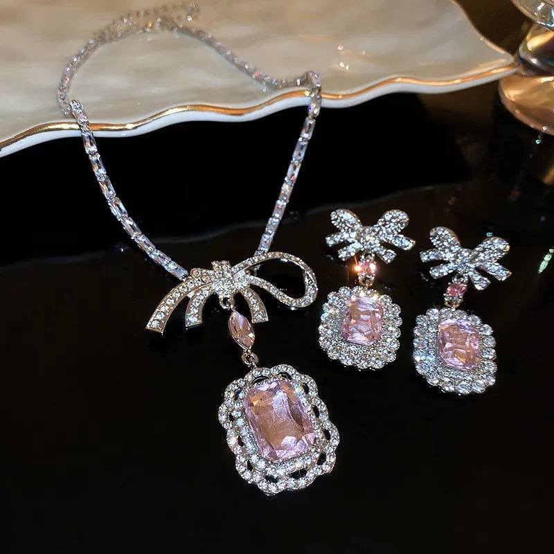Silver bow pendant necklace with crystal accents and matching drop earrings.