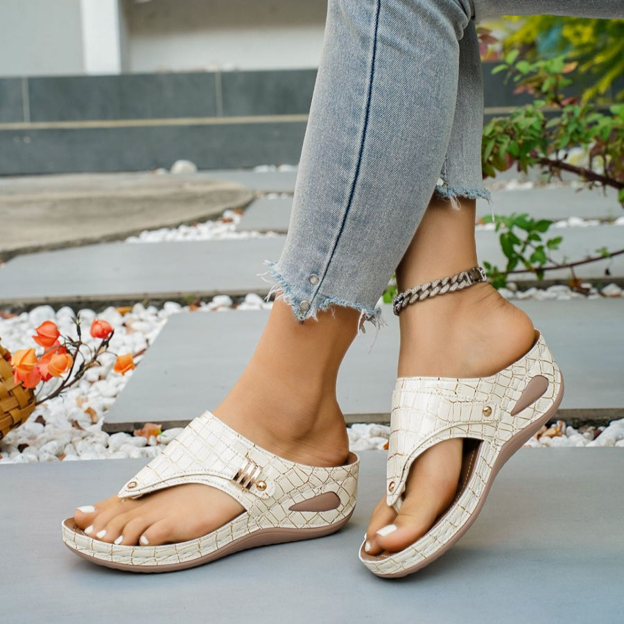 Beige crocodile-embossed wedge thong sandals with gold buckle detail.