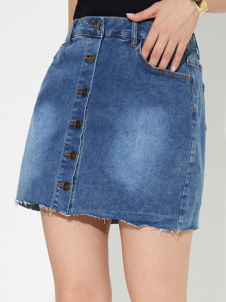 Button-front denim mini skirt in medium wash with raw hem and button closure.