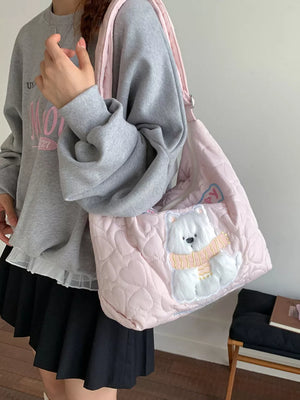 Blush pink quilted crossbody bag with heart pattern and a fluffy white bear applique wearing a scarf.