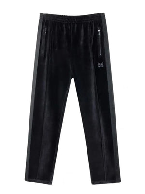 Black velour sweatpants with wide legs, side stripe, zip pockets, and butterfly emblem.