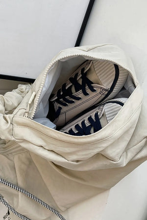 Gathered crescent shoulder bag in beige with navy laced sneakers inside