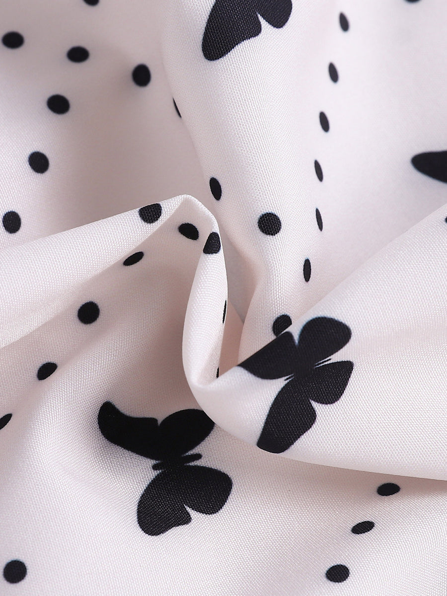 White baby dress with black butterfly and polka dot print.