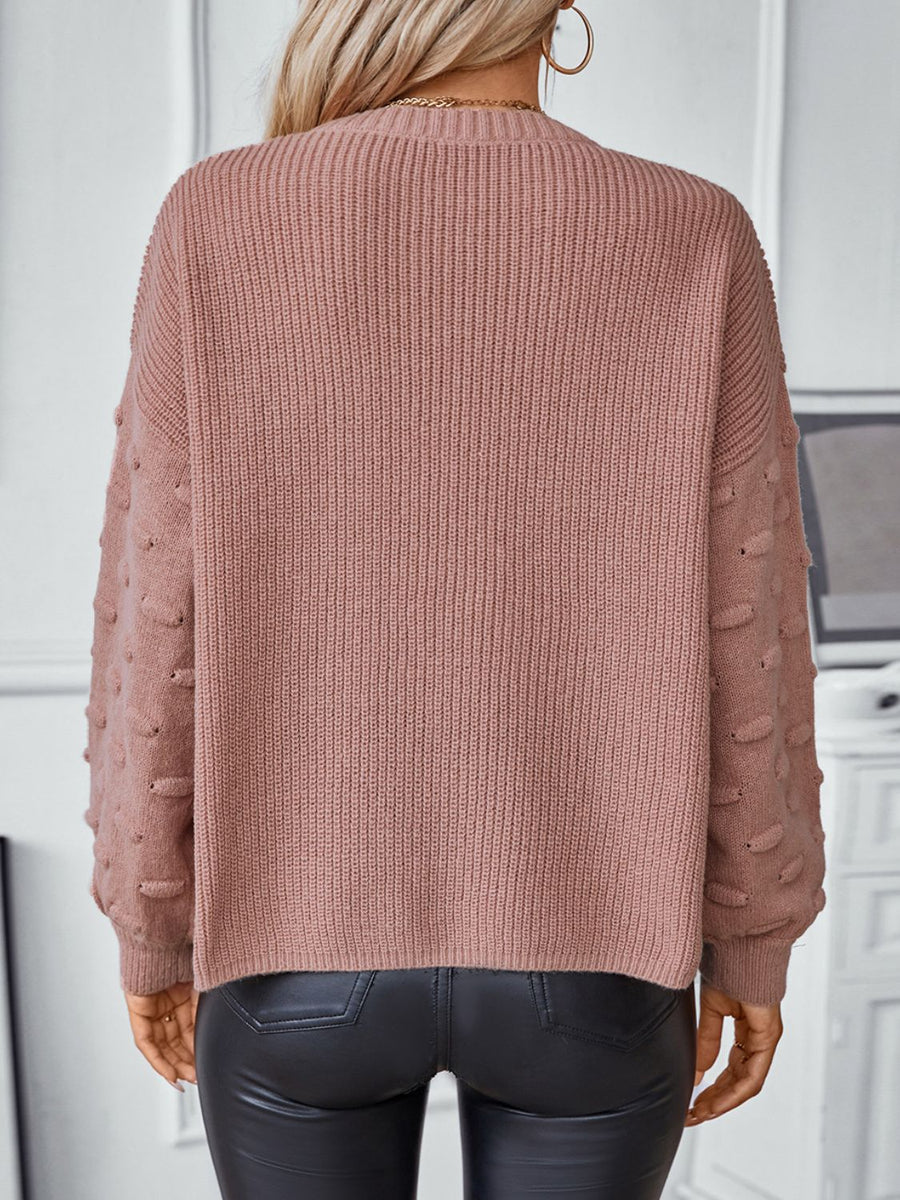 Dusty pink knit sweater with textured sleeve details and a ribbed crew neck.