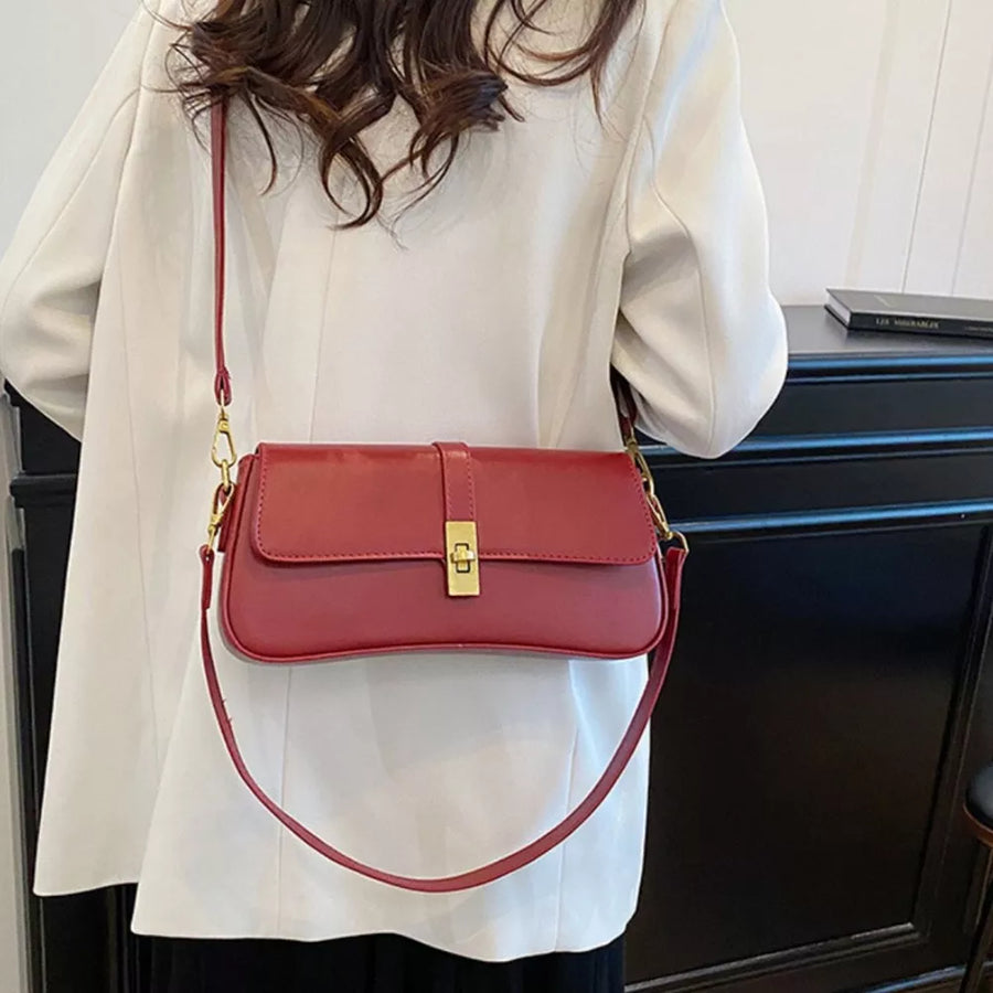 Red rectangular crossbody bag with gold clasp and adjustable strap.