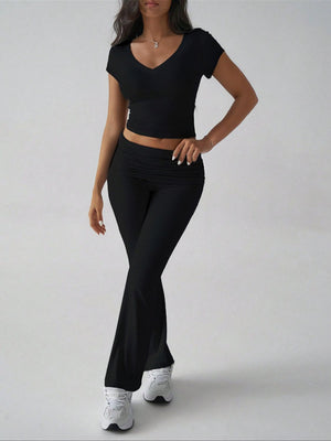 Black ribbed flare leg lounge set with v-neck crop top and ruched waistband pants.