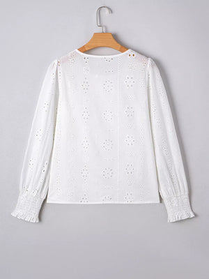 White cotton blouse with eyelet embroidery, ruffled cuffs, and smocked wrists.