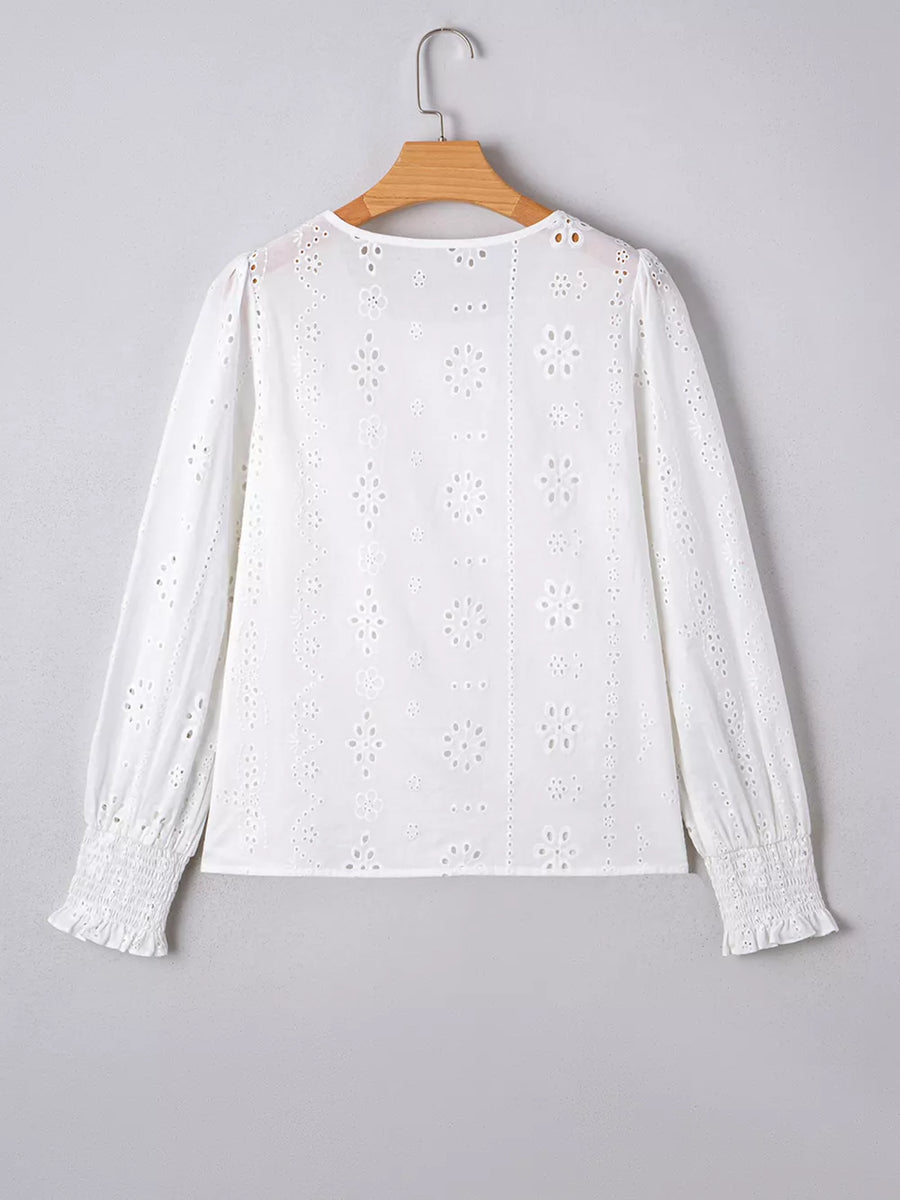 White cotton blouse with eyelet embroidery, ruffled cuffs, and smocked wrists.