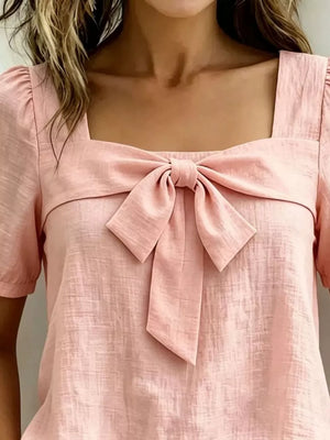 Pink puff sleeve shirt with square neckline and bow tie detail