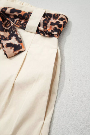Cream wide-leg pants with leopard print sash belt and side pockets.