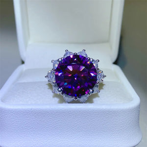 Deep purple sunburst moissanite cocktail ring with halo of small clear stones.