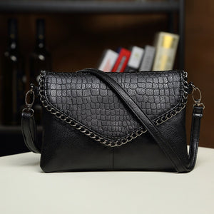 crossbody bag in black featuring chain strap detail and structured fit
