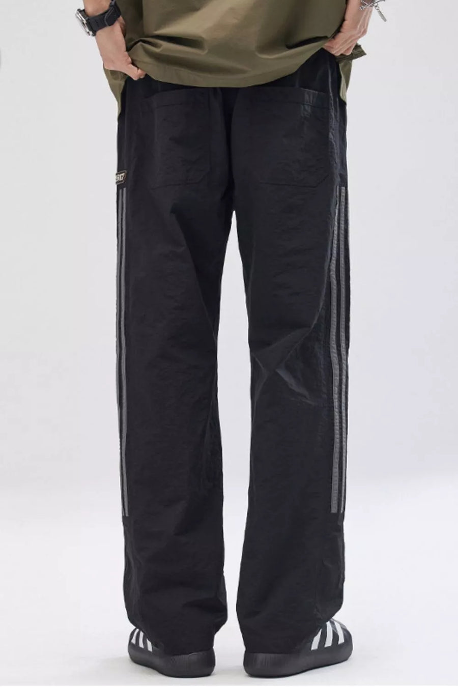 Black wide-leg cargo pants for men with reflective side stripes and back pockets.