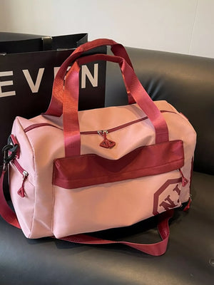 Pink Oxford cloth travel duffel bag with maroon accents and detachable strap.
