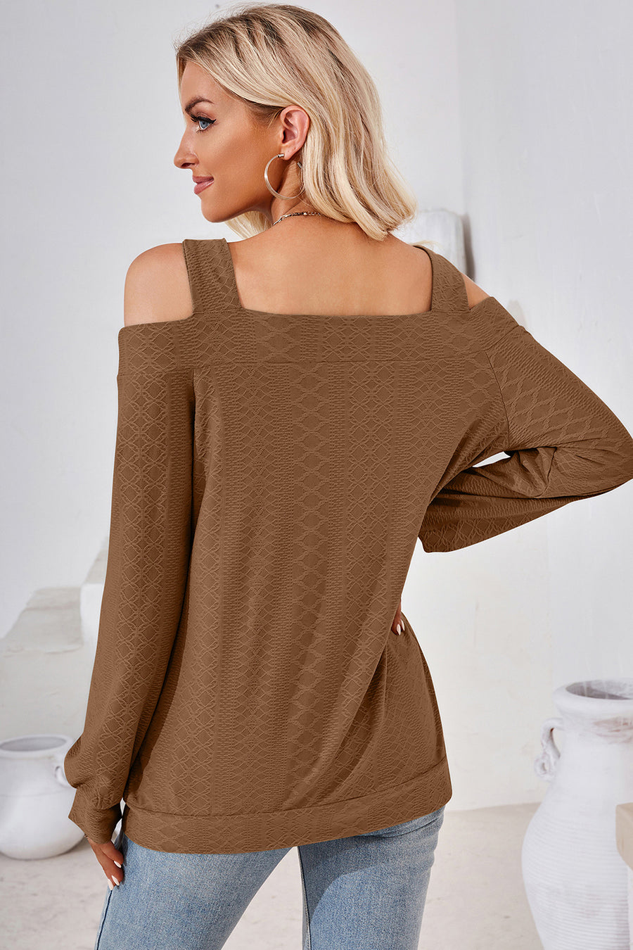 Brown geometric cutout shoulder top with long sleeves and a textured pattern.