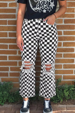 Checkerboard distressed cropped jeans with ripped knees and frayed hem.