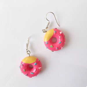 Pink donut dangle earrings with yellow icing and colorful sprinkles.
