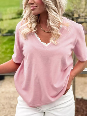 Pink V-neck knit top with delicate white lace trim and short sleeves.