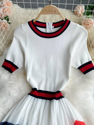 White midi dress with color block trim, pleated skirt, and short sleeves.