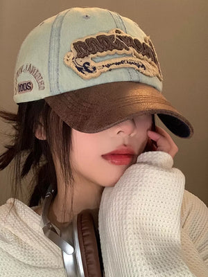 Distressed denim baseball cap in light cowboy blue with brown brim and embroidered logo.