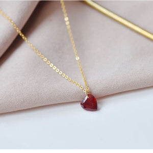 Gold chain necklace with a faceted red heart-shaped zircon pendant.
