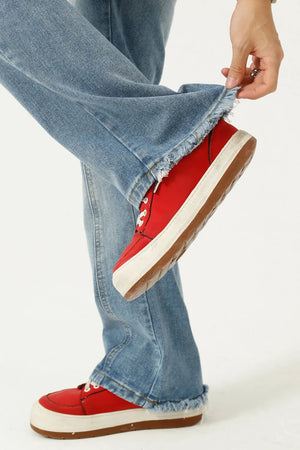 Seam detail flare jeans in medium wash denim with frayed hems styled with red sneakers.