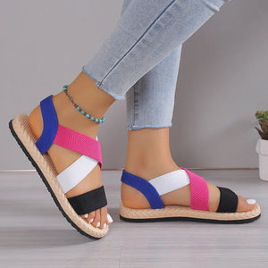 Crisscross elastic summer sandals with blue, pink, white, and black straps on a espadrille sole.