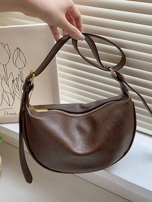 Brown crescent shoulder bag with adjustable strap and gold zipper detail
