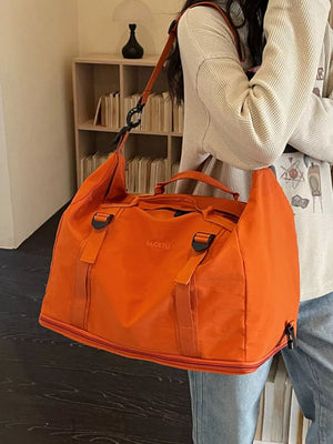 Orange nylon travel bag with buckle straps and crinkled texture.