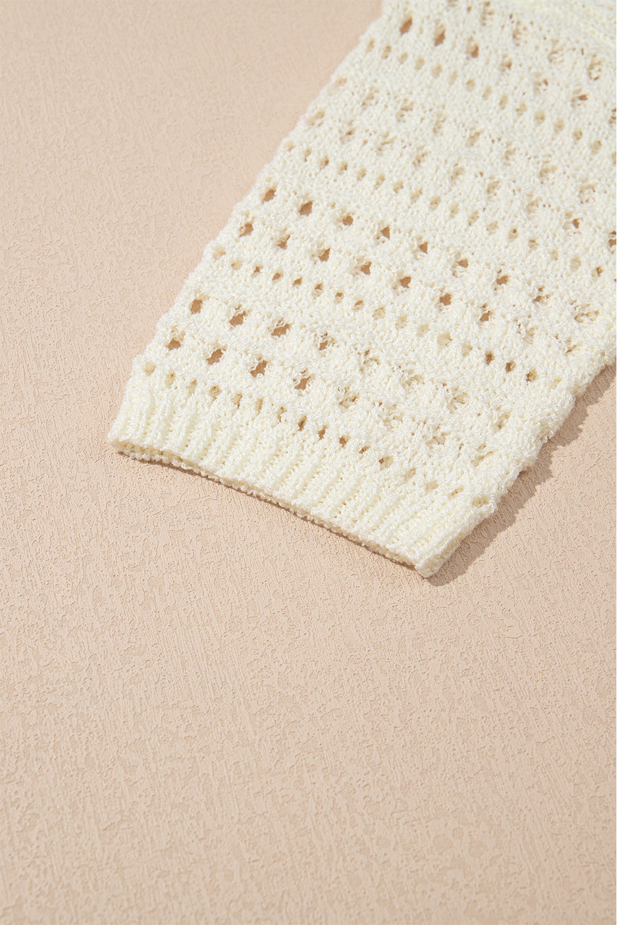 Beige openwork knit beach cover-up with ribbed cuff detail.