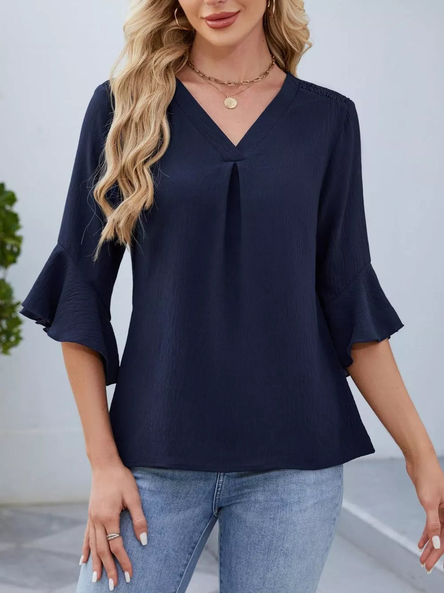 Navy V-neck blouse with ruffle sleeves and a textured fabric.