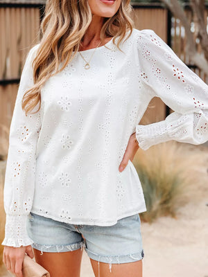White eyelet embroidered blouse with ruffled detail and smocked cuffs.