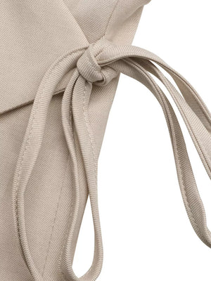 Chic beige sleeveless wrap top detail with tie closure, polyester fabric.