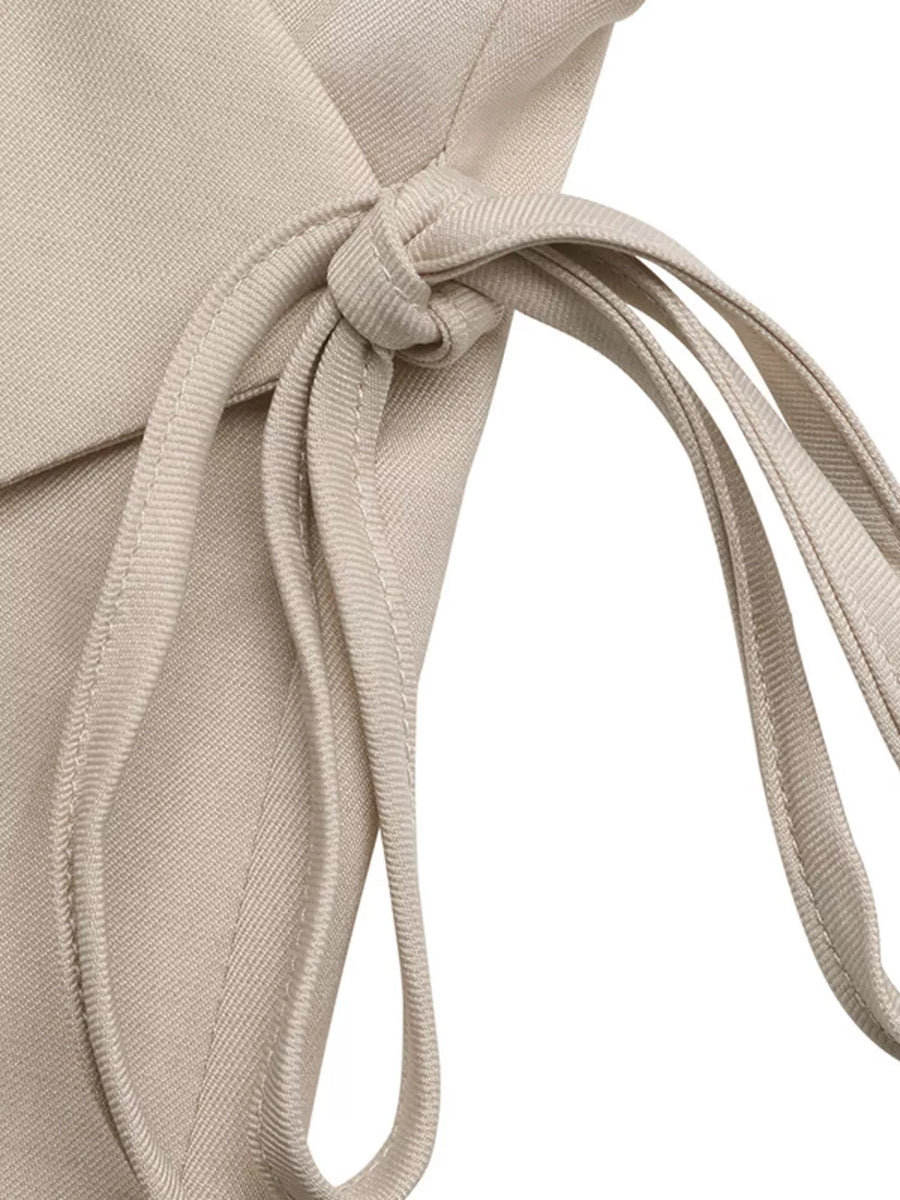 Chic beige sleeveless wrap top detail with tie closure, polyester fabric.