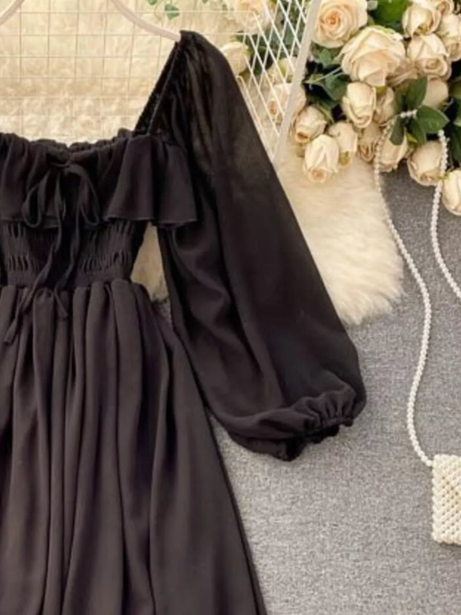 Black A-line maternity dress with square neck, ruffled trim, tie detail, and balloon sleeves.