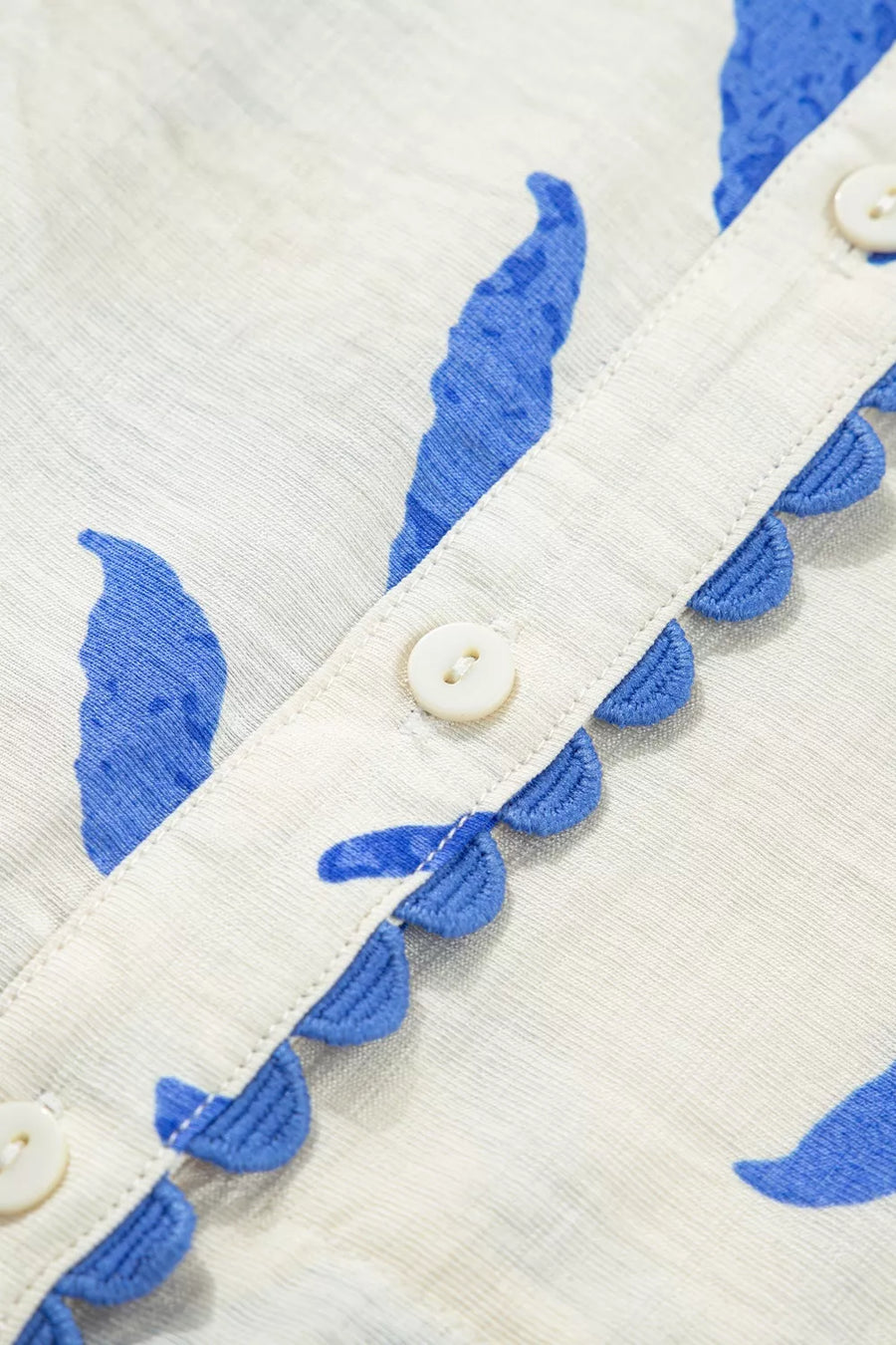 Maxi dress with blue botanical print, button front, and scalloped trim detail.
