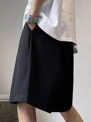Men's black loose-fit casual shorts with pockets, shown styled with a white t-shirt.