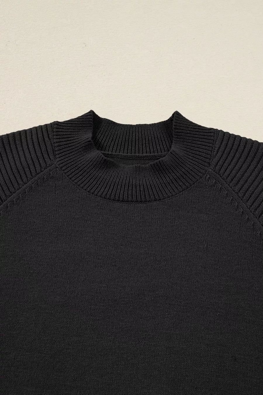 Black acrylic knit sweater with mock neck and ribbed balloon sleeves.