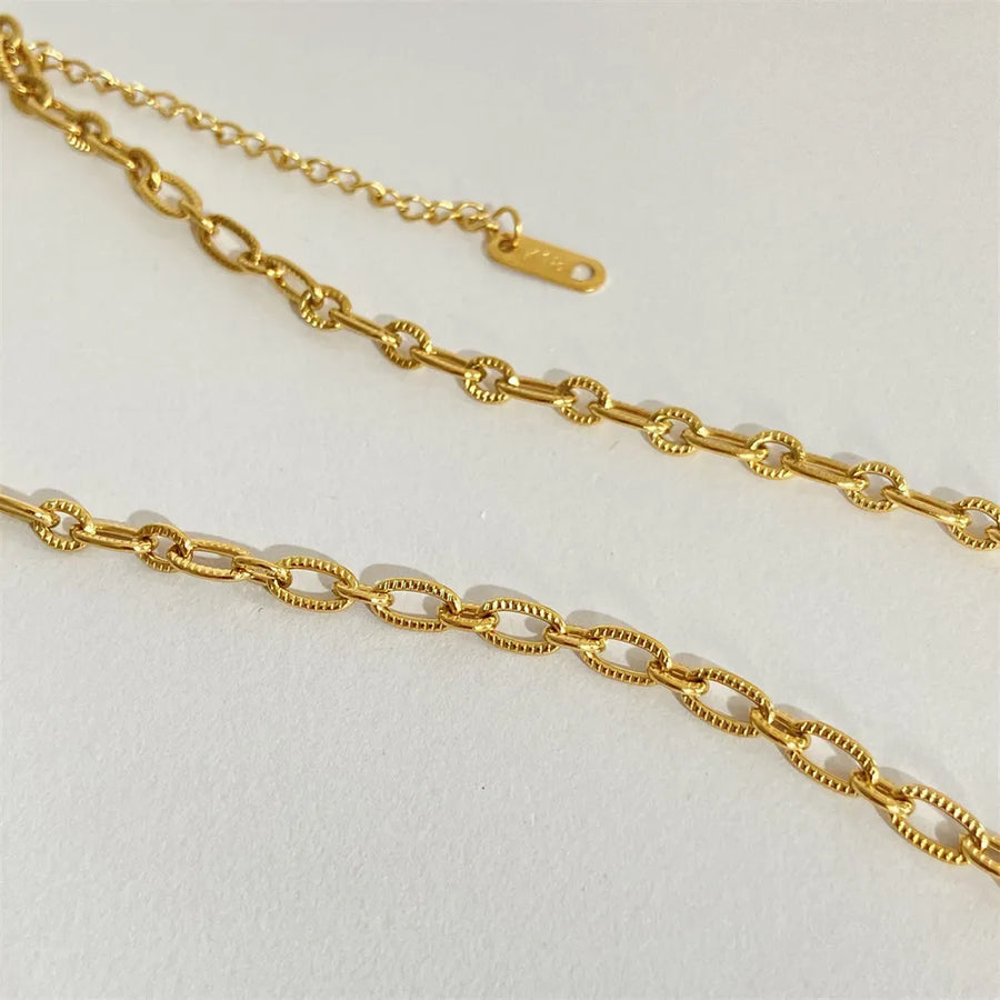Gold sunburst medallion chain necklace with textured oval links and adjustable clasp