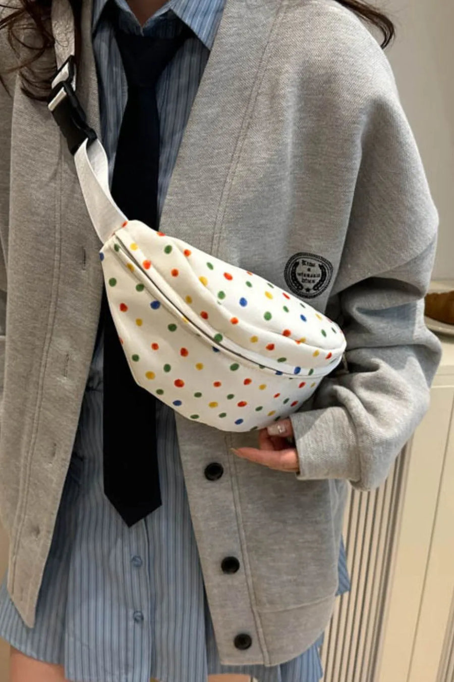 White belt bag with colorful polka dots and adjustable strap.